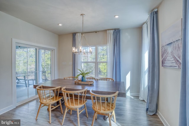 dining space with a notable chandelier, a wealth of natural light, and wood finished floors