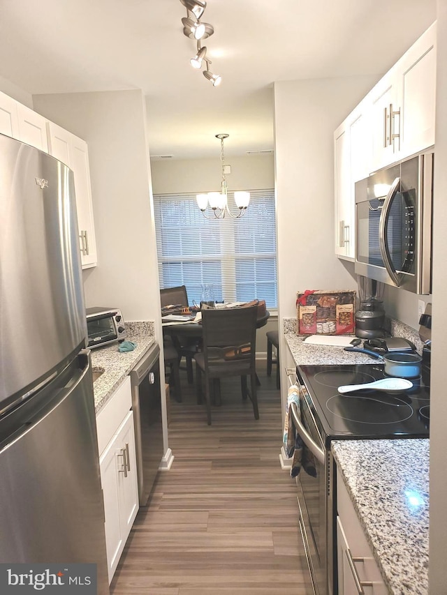 kitchen featuring light stone counters, a notable chandelier, wood finished floors, white cabinets, and appliances with stainless steel finishes