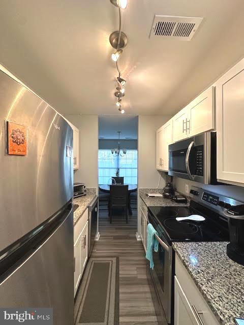 kitchen featuring visible vents, appliances with stainless steel finishes, white cabinets, and light stone counters