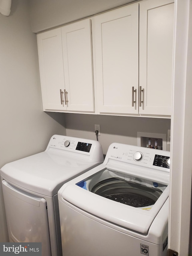 washroom with cabinet space and washing machine and dryer