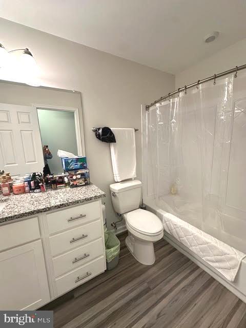 bathroom with vanity, shower / bath combo with shower curtain, wood finished floors, and toilet