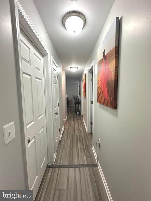 corridor featuring wood finished floors and baseboards