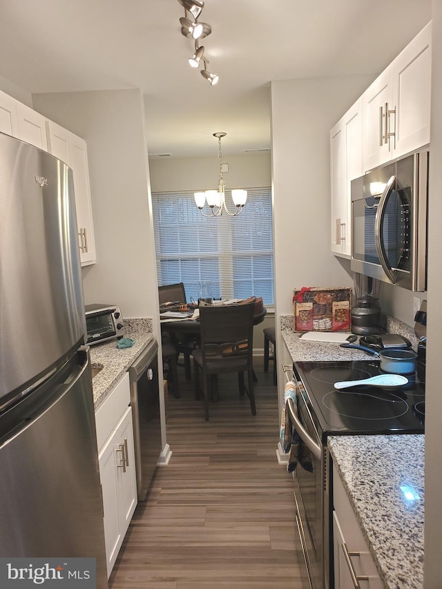 kitchen with white cabinets, light stone counters, wood finished floors, stainless steel appliances, and a chandelier