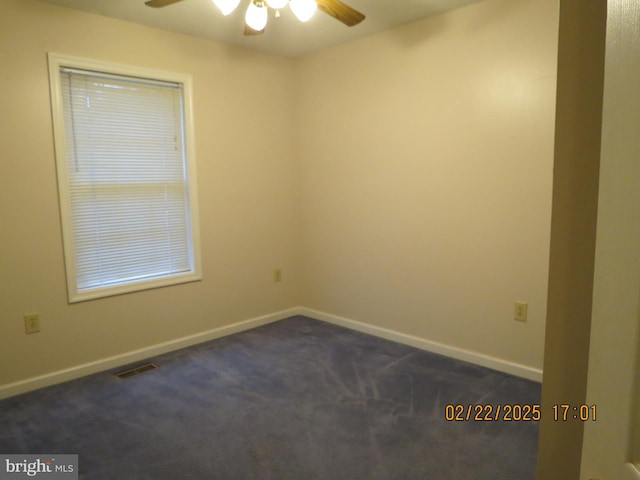 spare room with ceiling fan, baseboards, visible vents, and dark colored carpet