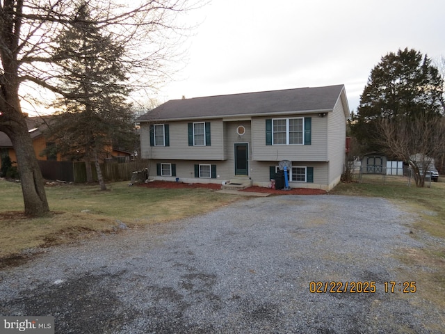 bi-level home featuring driveway, fence, a front lawn, and entry steps