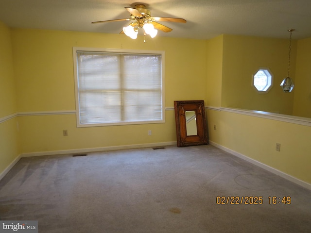 empty room featuring carpet floors, visible vents, baseboards, and a ceiling fan