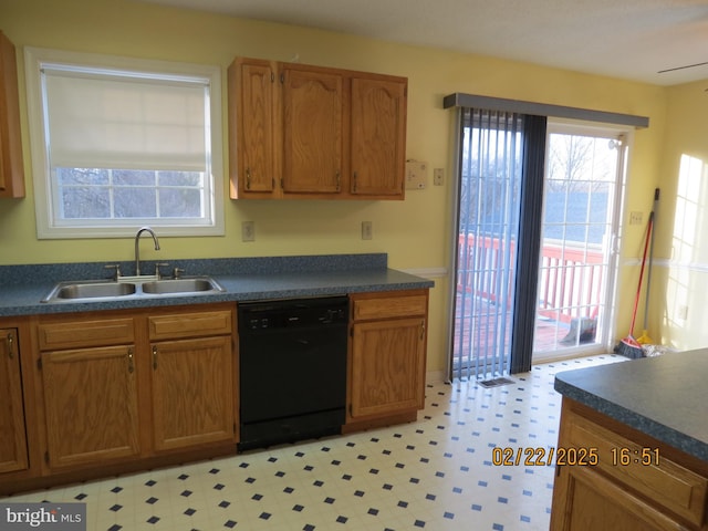 kitchen with a sink, dark countertops, and dishwasher