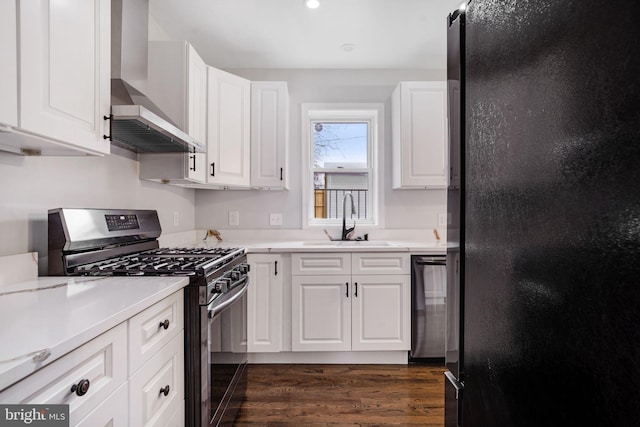 kitchen featuring dishwasher, stainless steel range with gas stovetop, freestanding refrigerator, wall chimney range hood, and a sink