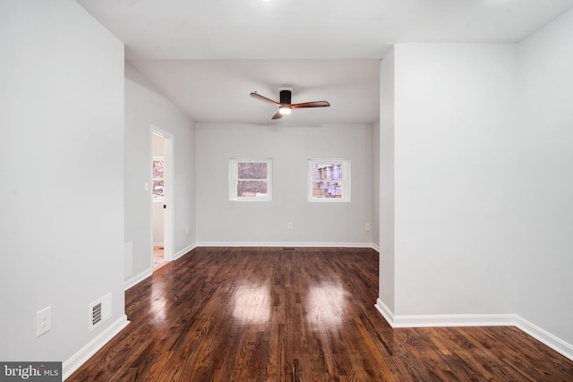 unfurnished room with visible vents, baseboards, ceiling fan, and dark wood-type flooring