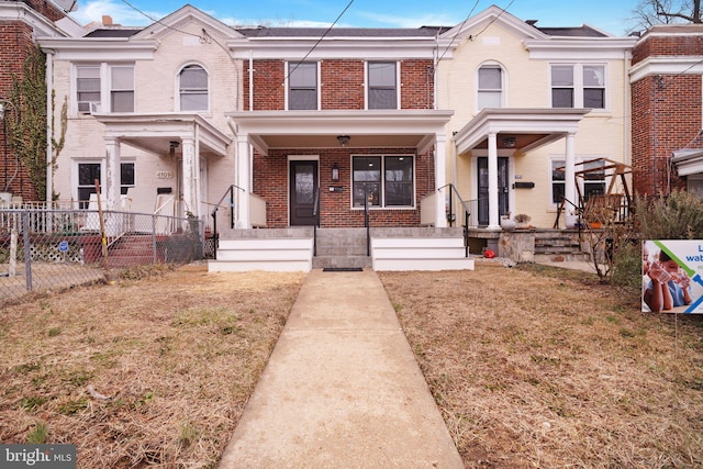 multi unit property with a front yard, fence, and brick siding