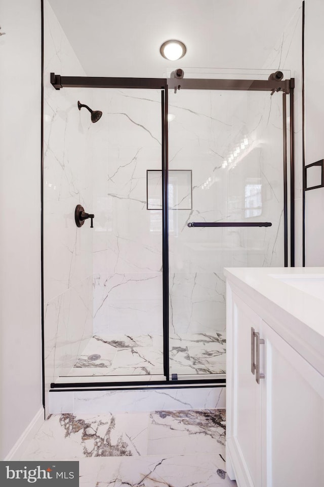 bathroom featuring marble finish floor, a marble finish shower, and vanity