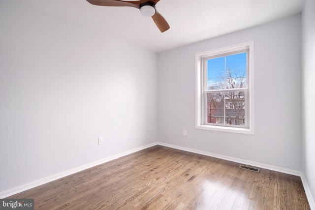 spare room with baseboards, visible vents, ceiling fan, and wood finished floors