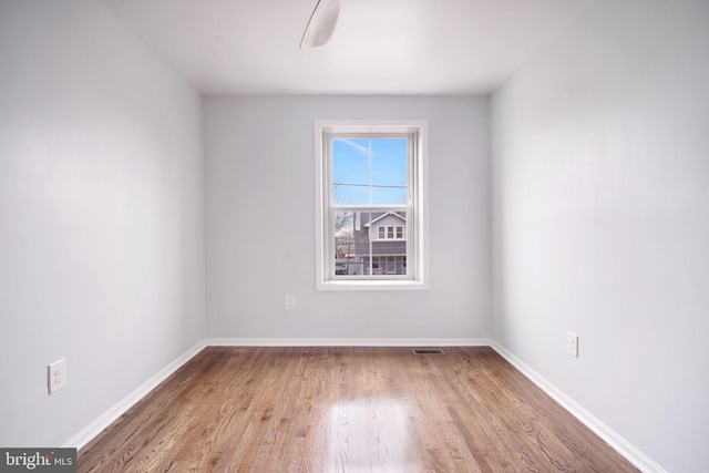 unfurnished room with wood finished floors, visible vents, and baseboards