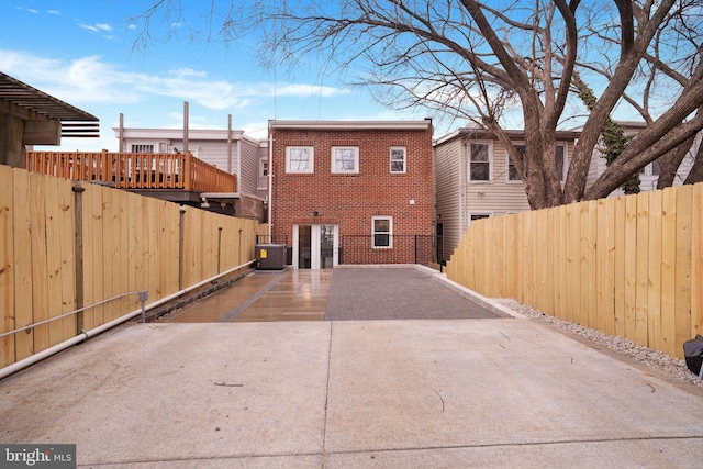 back of property with central AC, brick siding, a patio, and fence