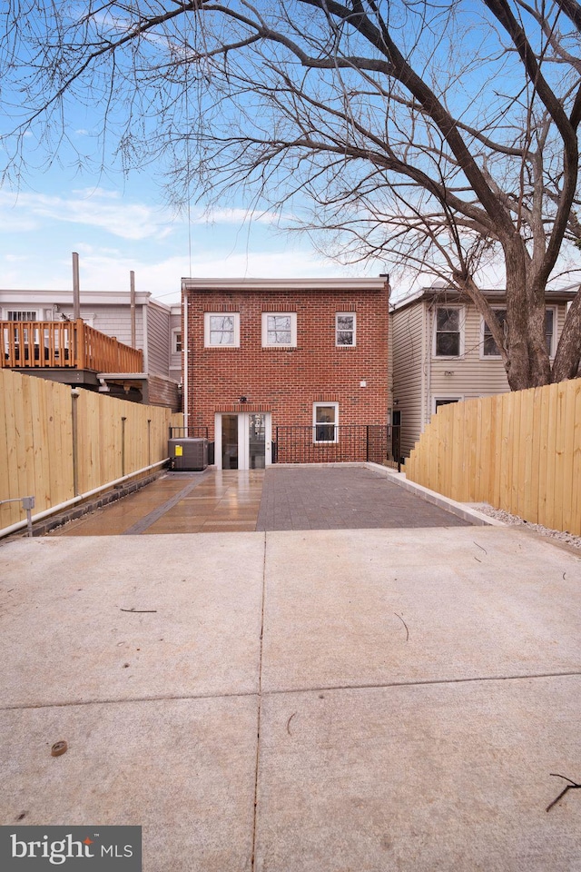 rear view of property with brick siding, cooling unit, and fence