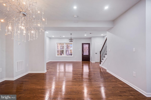 interior space featuring baseboards, visible vents, stairway, and wood finished floors