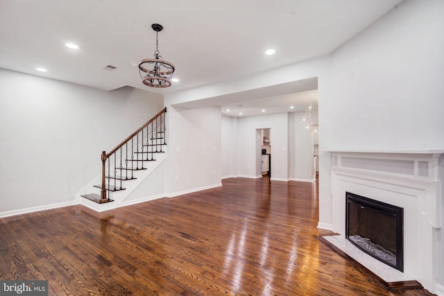 unfurnished living room featuring stairs, visible vents, a fireplace, and hardwood / wood-style flooring