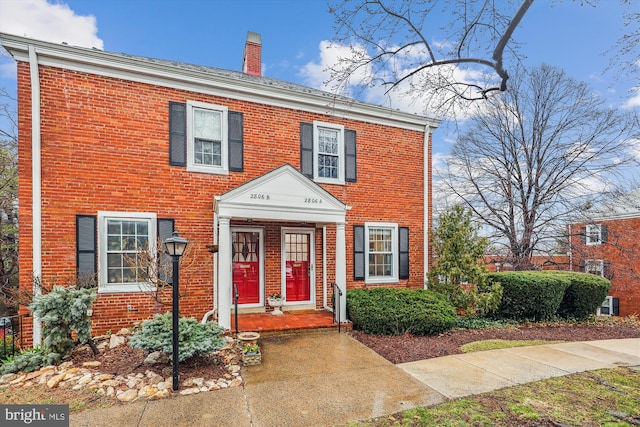 view of front of home with brick siding and a chimney