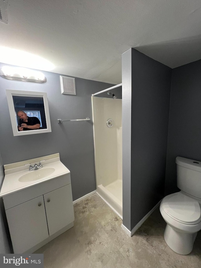 full bathroom featuring toilet, visible vents, a walk in shower, and vanity