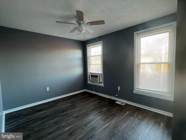 empty room featuring cooling unit, baseboards, visible vents, and dark wood-type flooring