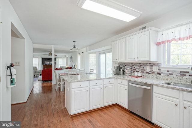 kitchen featuring visible vents, dishwasher, a peninsula, white cabinetry, and a sink