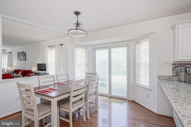 dining area with a wealth of natural light, wood-type flooring, and baseboards