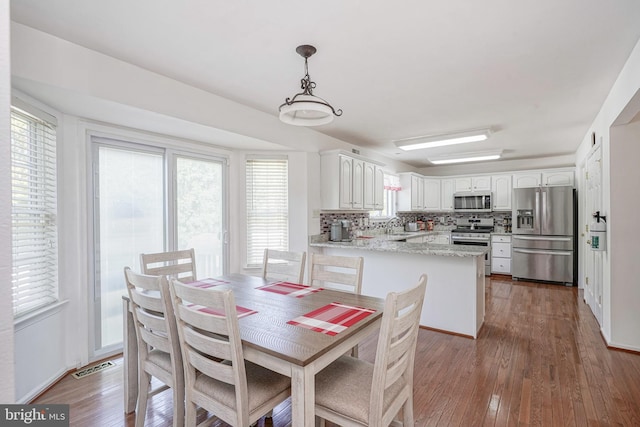 dining space with wood-type flooring and visible vents