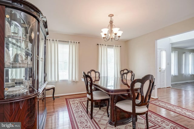 dining area with a chandelier, hardwood / wood-style floors, and baseboards