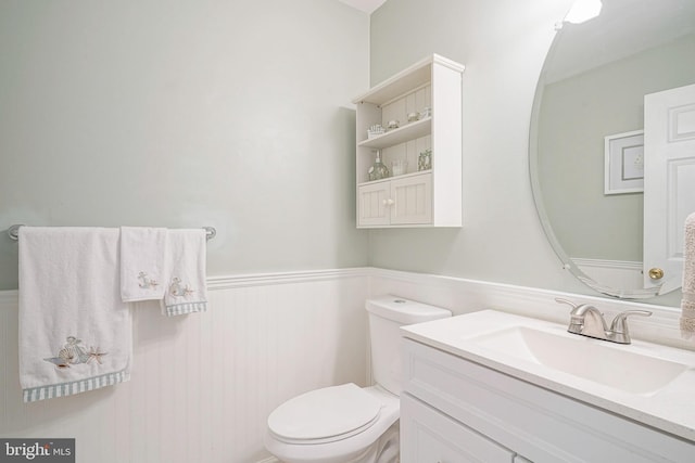 bathroom featuring toilet, vanity, and wainscoting