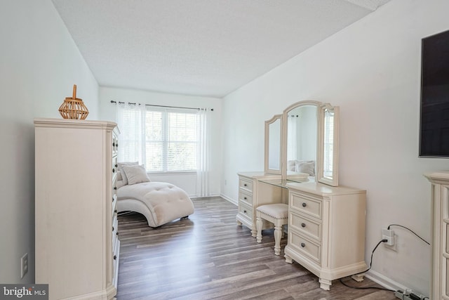 bedroom with a textured ceiling, baseboards, and wood finished floors