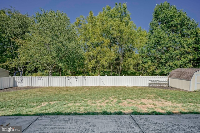 view of yard featuring a fenced backyard, a storage unit, and an outbuilding