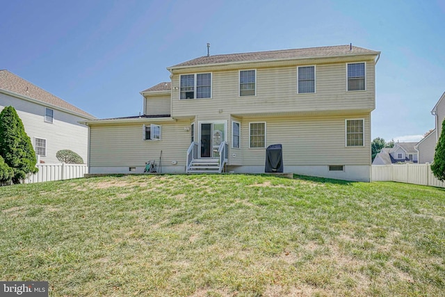 rear view of house featuring entry steps, crawl space, a yard, and fence