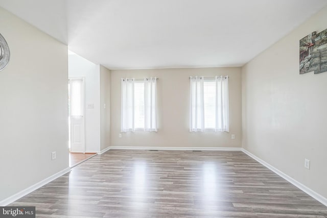 spare room with baseboards and wood finished floors