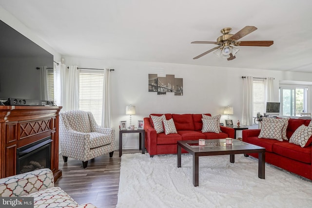 living room with a ceiling fan, wood finished floors, and a glass covered fireplace