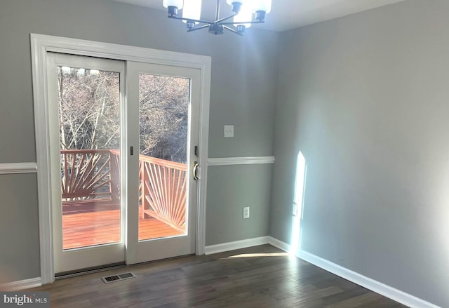 doorway to outside featuring visible vents, baseboards, an inviting chandelier, and wood finished floors