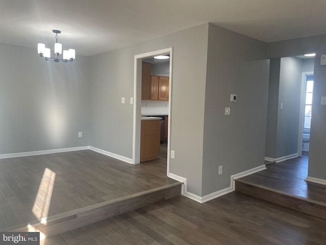 unfurnished dining area featuring baseboards, a notable chandelier, and dark wood-style flooring