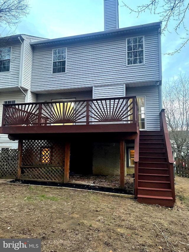 rear view of house with a wooden deck, stairway, and a chimney