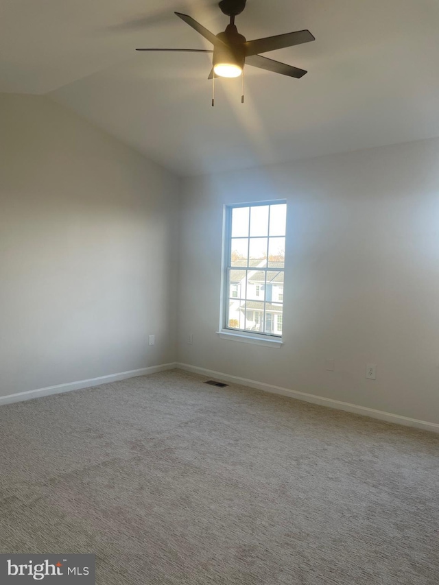 carpeted spare room featuring lofted ceiling, baseboards, visible vents, and ceiling fan