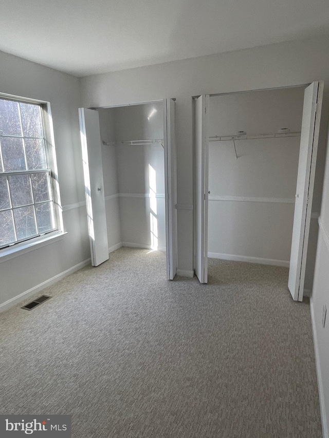 unfurnished bedroom with visible vents, carpet floors, and baseboards