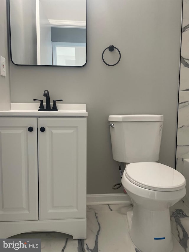 bathroom with baseboards, toilet, marble finish floor, and vanity