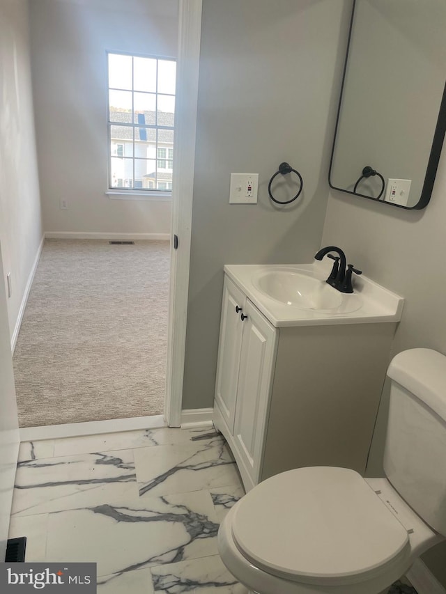 half bathroom featuring visible vents, toilet, marble finish floor, baseboards, and vanity