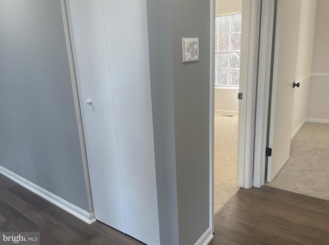 corridor with dark wood-type flooring and baseboards