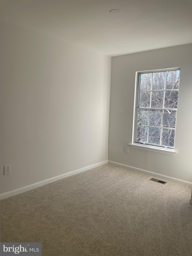 carpeted spare room featuring baseboards and visible vents