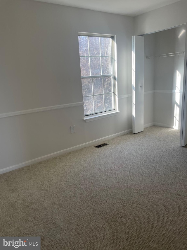 spare room featuring carpet flooring, baseboards, and visible vents