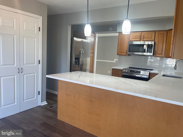 kitchen with a sink, dark wood-type flooring, light stone counters, and stainless steel appliances