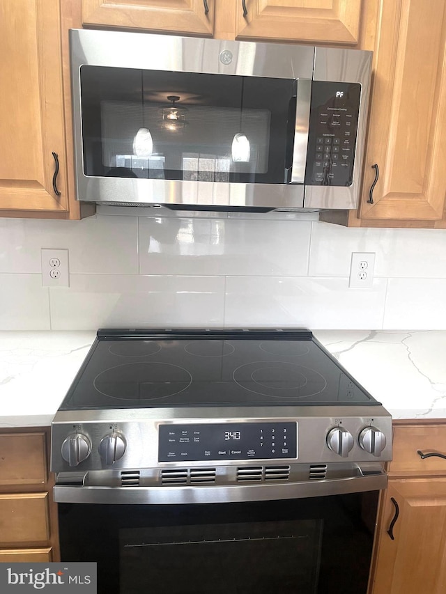 kitchen featuring tasteful backsplash, appliances with stainless steel finishes, and light stone countertops