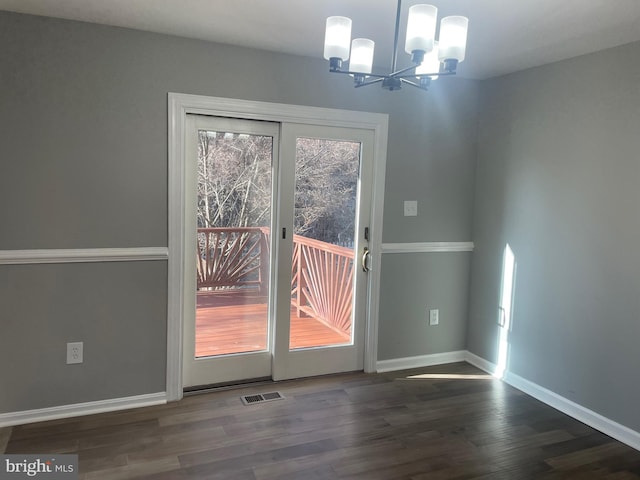 doorway featuring a notable chandelier, visible vents, baseboards, and wood finished floors