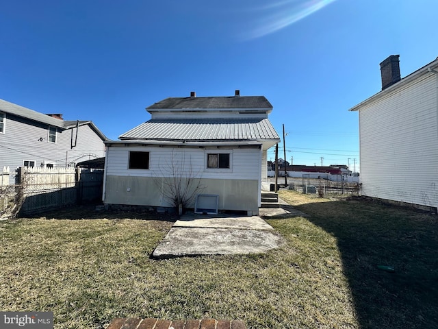 back of house featuring metal roof, a yard, and fence