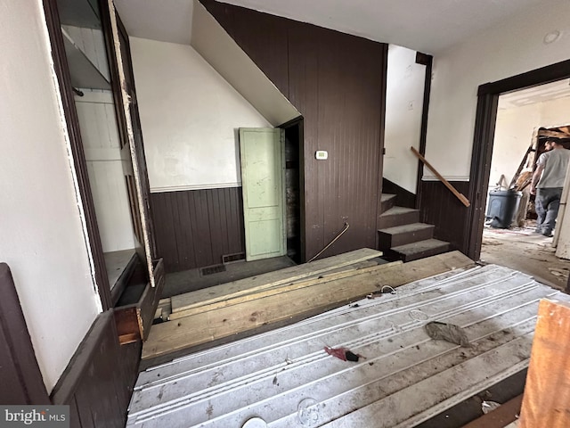 stairs featuring wooden walls and wainscoting