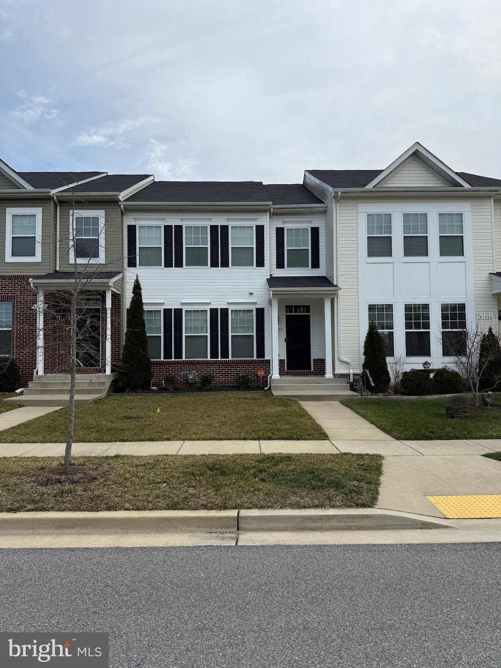 view of property featuring a front lawn and brick siding